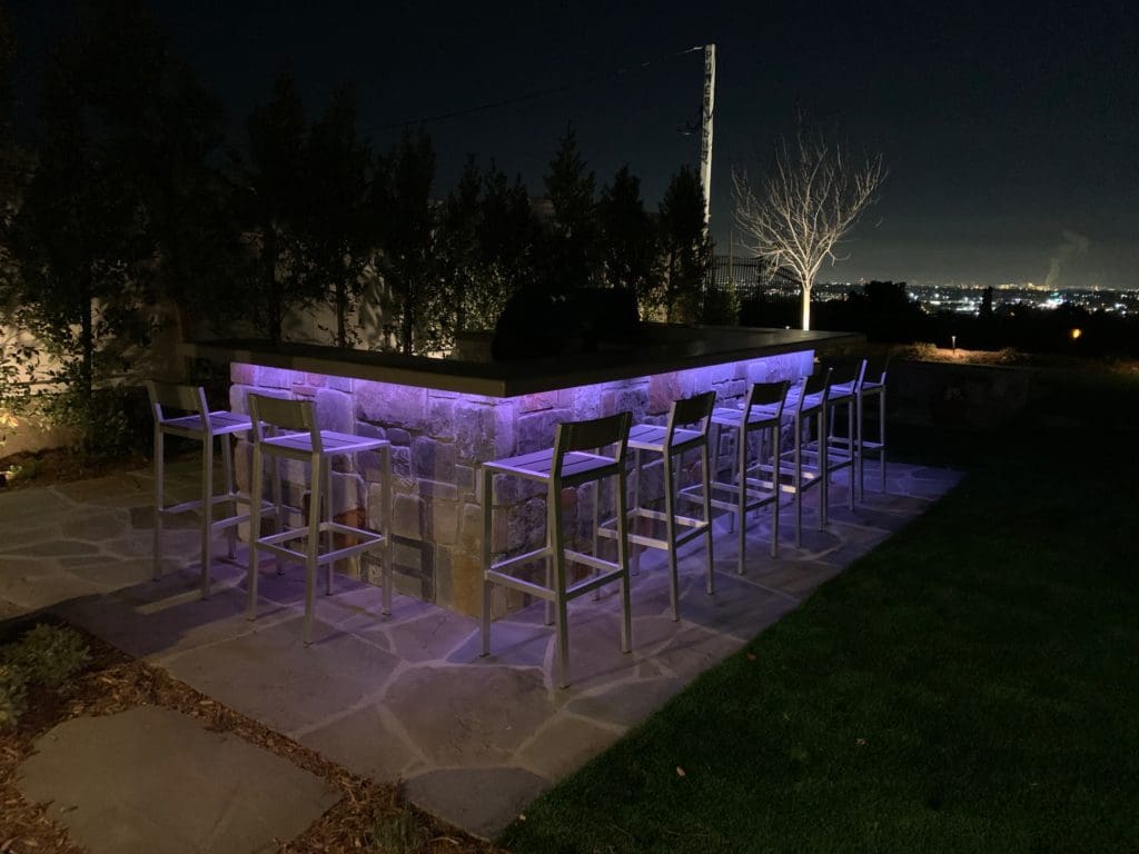 Evening outdoor kitchen and bar with low-voltage LED accent lighting in a Lowcountry landscape