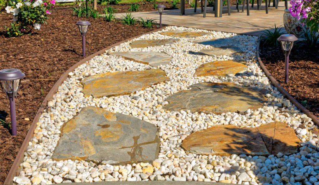 Flagstone and river rock path with a clean curved bed edge dividing planting beds in a Lowcountry garden