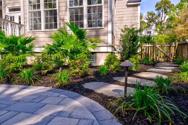 Layered foundation planting set back from the wall of a Lowcountry home, with a paver walk and windows kept clear