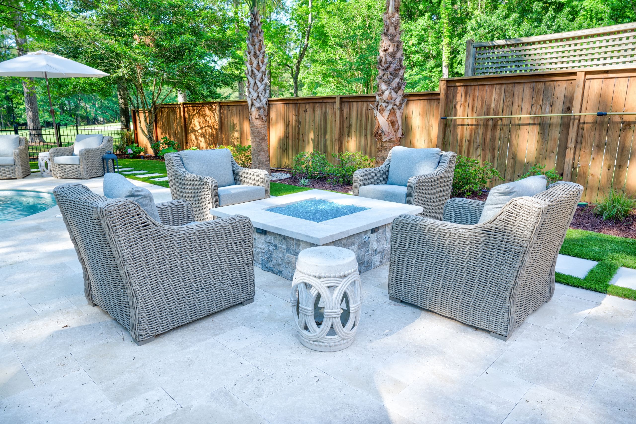 Travertine paver patio with a fire feature and lounge seating in a Lowcountry backyard, designed by MP Landscape Design